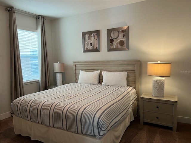 bedroom featuring dark carpet and baseboards