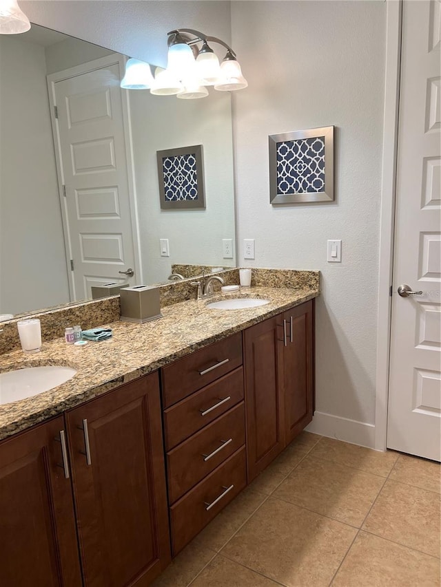 bathroom with baseboards, double vanity, a sink, and tile patterned floors