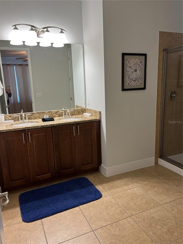 bathroom featuring double vanity, a stall shower, tile patterned flooring, and a sink