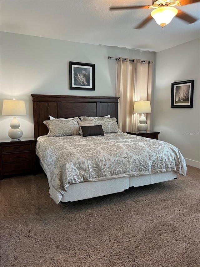 bedroom featuring ceiling fan, a textured ceiling, dark carpet, and baseboards