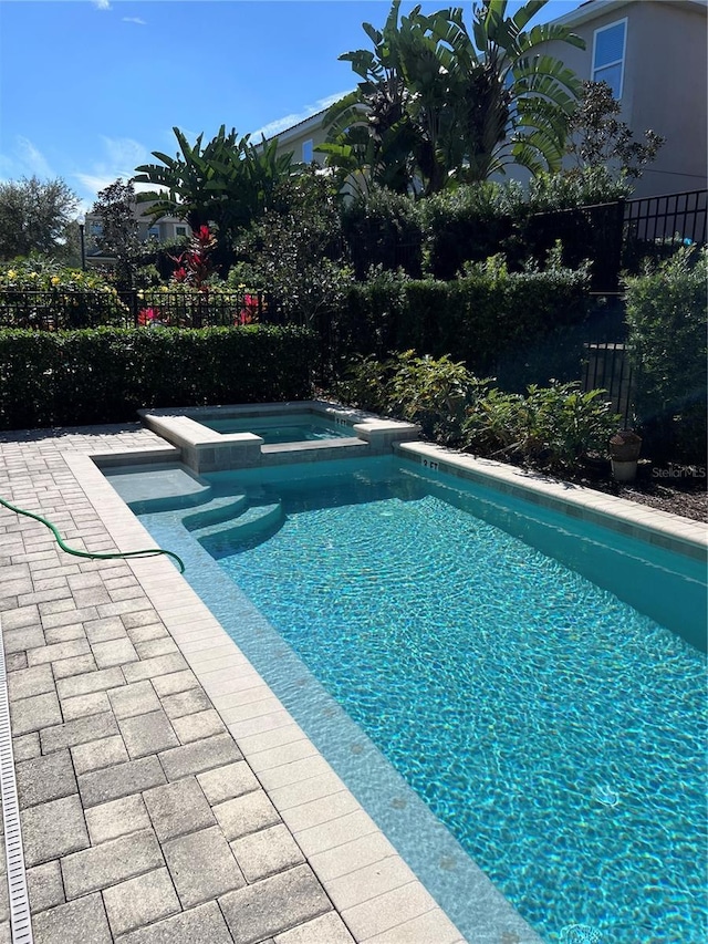 view of pool featuring a pool with connected hot tub and fence