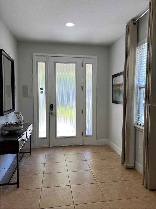 entrance foyer featuring light tile patterned floors, a textured ceiling, and baseboards