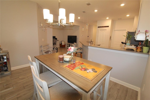 dining area with wood-type flooring, a notable chandelier, and sink