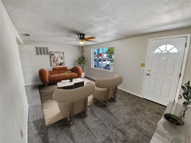 carpeted living room with ceiling fan and a textured ceiling