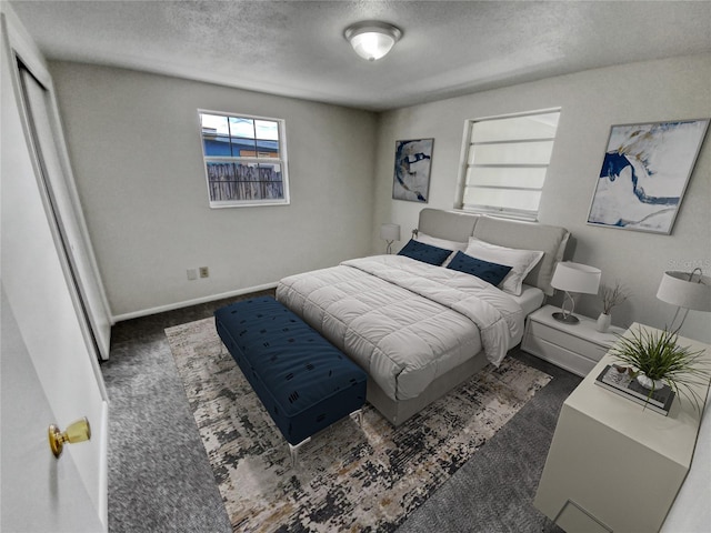 bedroom with a textured ceiling and dark carpet