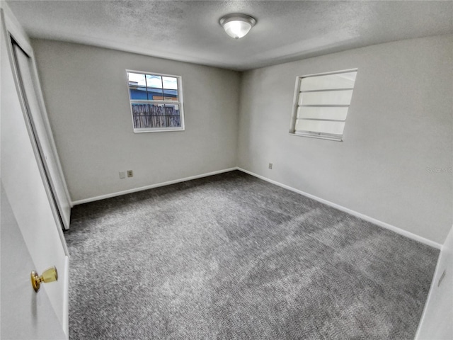 spare room with built in features, a textured ceiling, and dark carpet