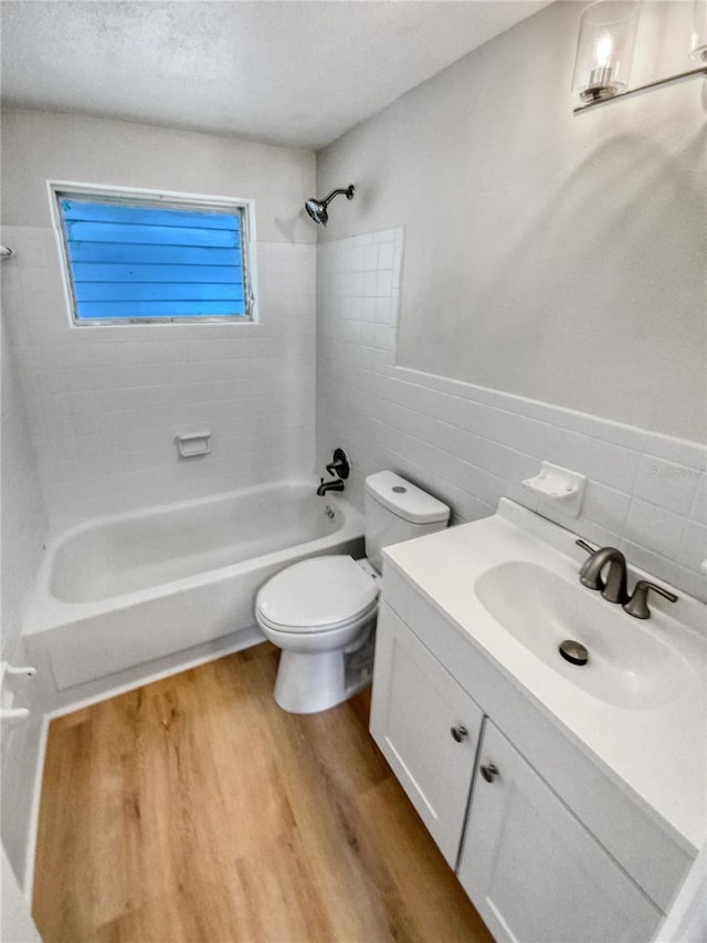 full bathroom featuring tiled shower / bath, toilet, hardwood / wood-style floors, and vanity