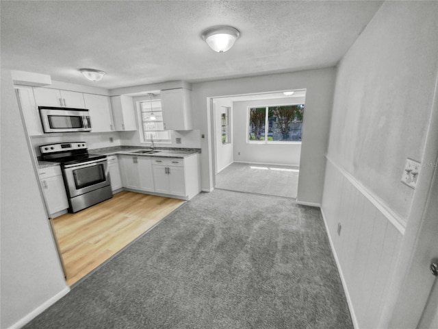 kitchen with white cabinets, light hardwood / wood-style flooring, appliances with stainless steel finishes, and sink