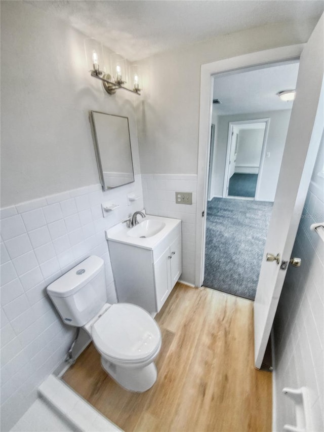 bathroom featuring vanity, toilet, hardwood / wood-style flooring, and tile walls