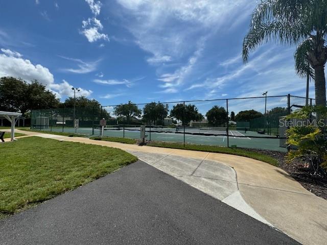 view of property's community featuring tennis court and a yard