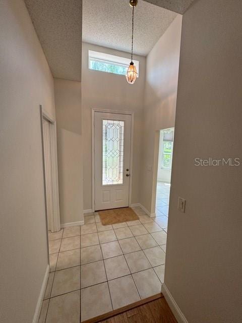 entrance foyer featuring light tile patterned floors, a wealth of natural light, a textured ceiling, and a towering ceiling