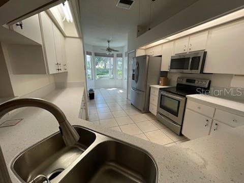 kitchen with appliances with stainless steel finishes, white cabinetry, and ceiling fan