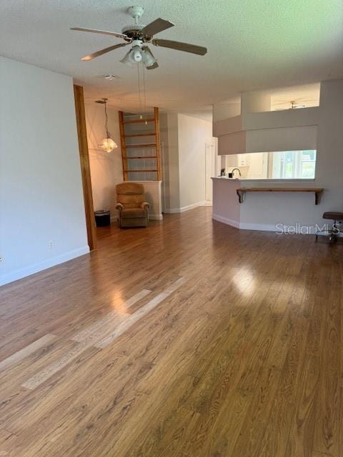 unfurnished living room with ceiling fan, dark hardwood / wood-style floors, and sink