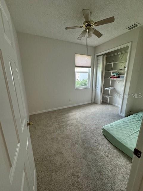 unfurnished bedroom featuring a textured ceiling, ceiling fan, a closet, and carpet floors