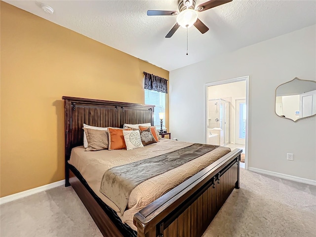 bedroom with a textured ceiling, ceiling fan, ensuite bathroom, and light colored carpet