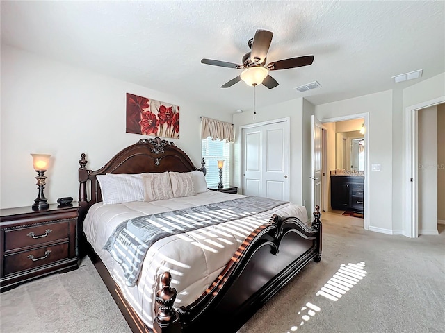 carpeted bedroom featuring ensuite bath, a closet, ceiling fan, and a textured ceiling