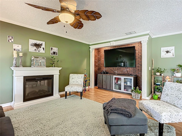 living room with light hardwood / wood-style floors, ceiling fan, a textured ceiling, and crown molding