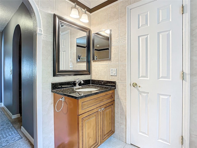 bathroom featuring tile walls, tile flooring, ornamental molding, and vanity