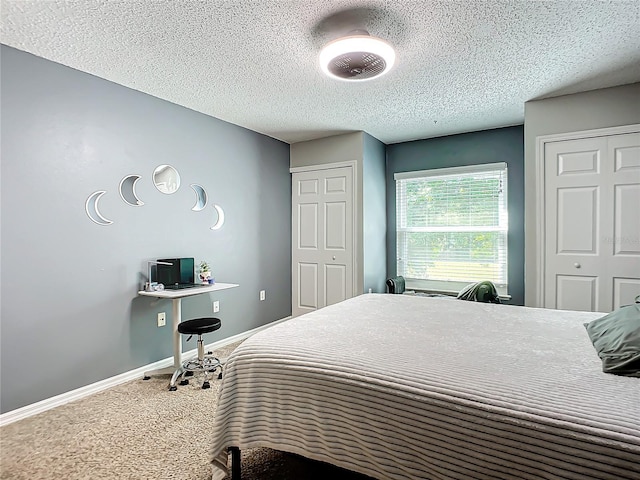 bedroom with carpet flooring, a textured ceiling, and multiple closets