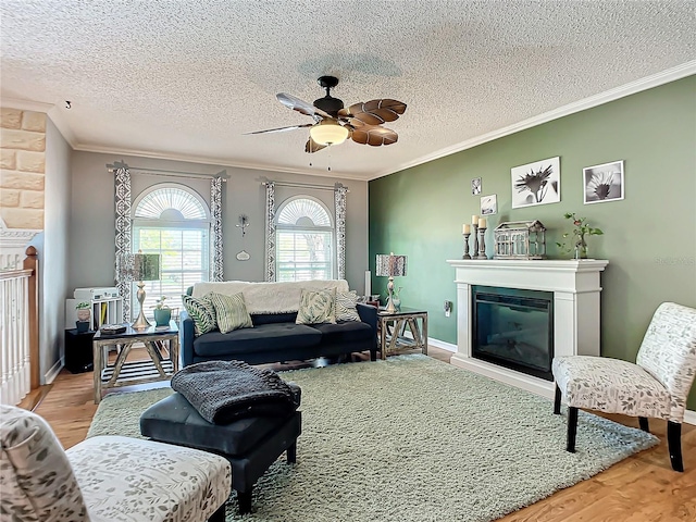 living room with light hardwood / wood-style floors, a textured ceiling, ceiling fan, and ornamental molding