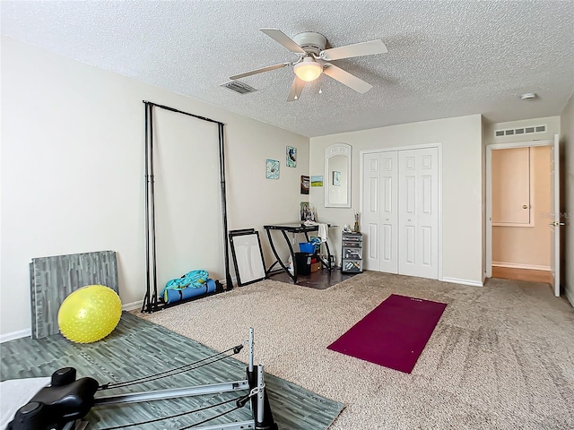 workout room featuring carpet floors, a textured ceiling, and ceiling fan