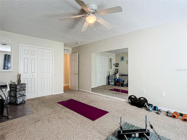 exercise area with dark colored carpet, ceiling fan, and a textured ceiling