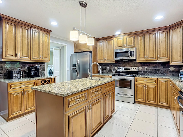 kitchen with tasteful backsplash, a center island with sink, appliances with stainless steel finishes, and light tile floors