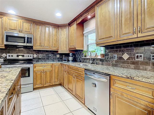 kitchen with light stone counters, backsplash, sink, and stainless steel appliances