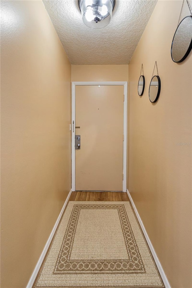 doorway featuring a textured ceiling and light wood-type flooring