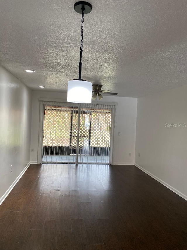 spare room featuring a healthy amount of sunlight, a textured ceiling, ceiling fan, and dark hardwood / wood-style floors