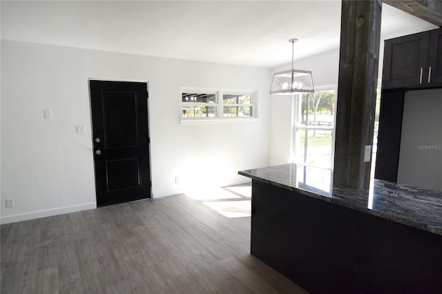 kitchen featuring decorative light fixtures, dark hardwood / wood-style floors, dark stone counters, and a chandelier