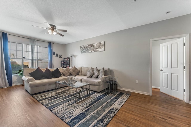 living room featuring dark hardwood / wood-style floors, ceiling fan, and a textured ceiling