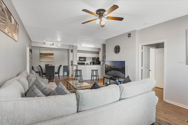 living room featuring ceiling fan, wood-type flooring, and track lighting