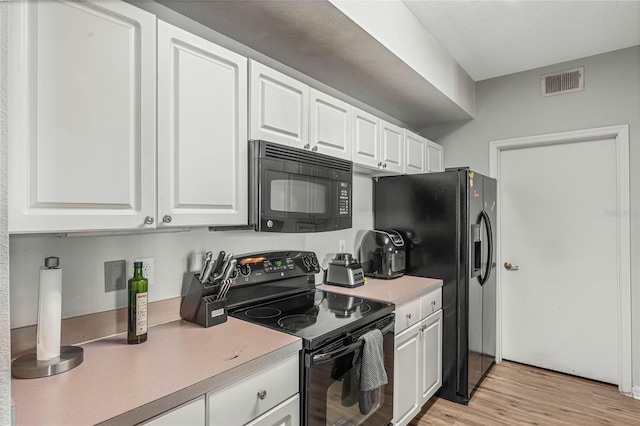 kitchen with white cabinets, black appliances, and light hardwood / wood-style floors