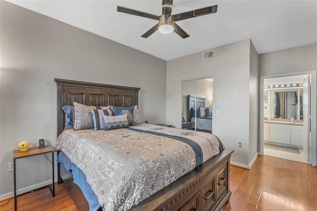 bedroom featuring ceiling fan, light wood-type flooring, ensuite bathroom, and a closet