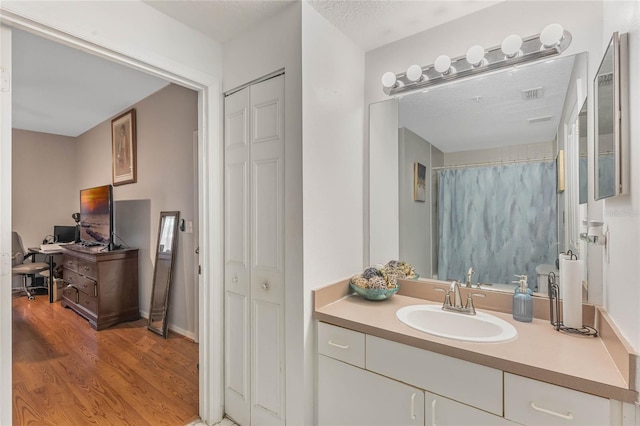 bathroom with vanity, wood-type flooring, and a textured ceiling