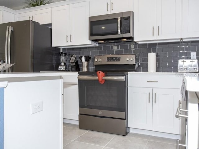 kitchen with light tile patterned floors, backsplash, white cabinetry, and stainless steel appliances