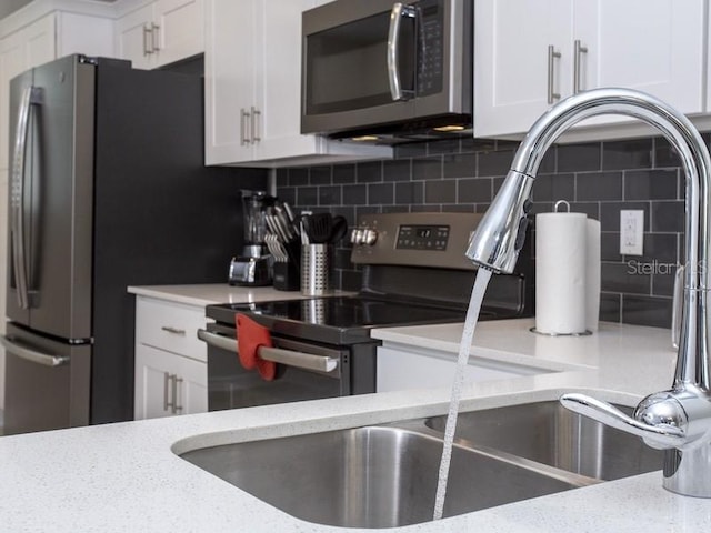 kitchen with tasteful backsplash, white cabinetry, light stone counters, and stainless steel appliances