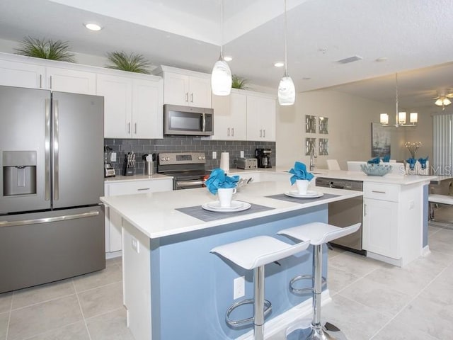 kitchen with appliances with stainless steel finishes, decorative backsplash, white cabinets, and hanging light fixtures