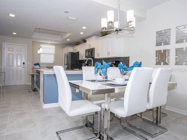 dining area featuring light tile patterned flooring, a raised ceiling, and an inviting chandelier