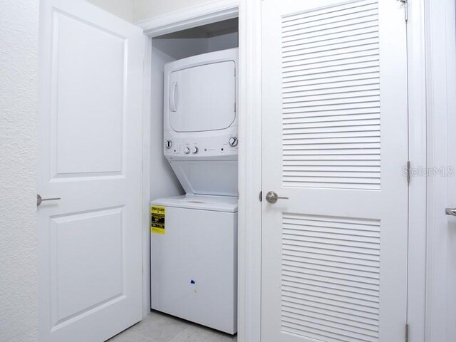 laundry area with stacked washer and dryer and light tile patterned floors