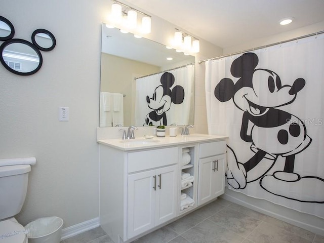 bathroom with curtained shower, double vanity, toilet, and a sink