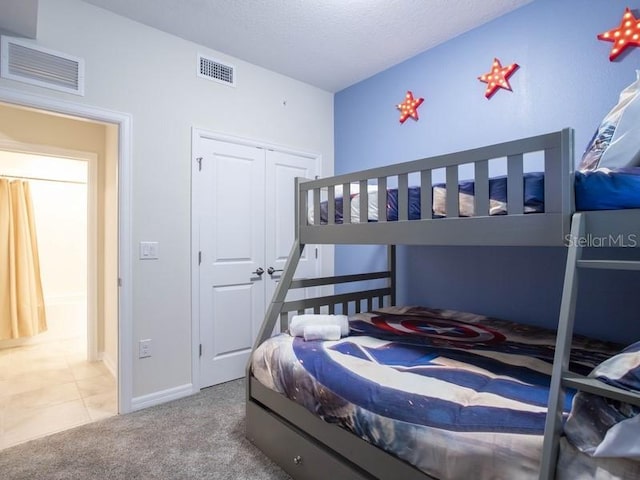 carpeted bedroom with a closet and a textured ceiling