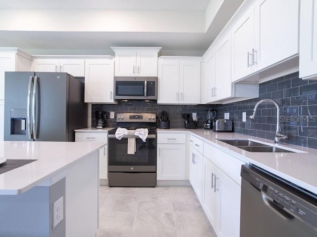 kitchen with backsplash, light tile patterned floors, sink, appliances with stainless steel finishes, and white cabinets