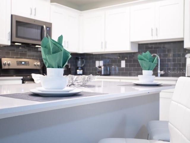 kitchen featuring backsplash, appliances with stainless steel finishes, and white cabinets