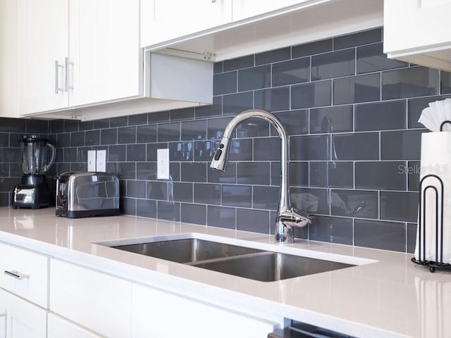 kitchen featuring white cabinetry, backsplash, and sink