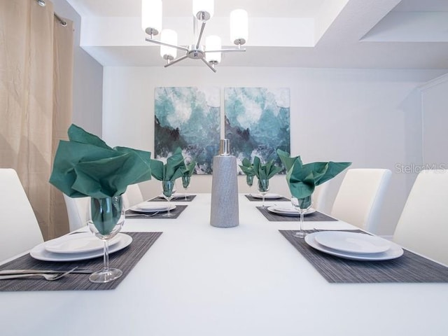 dining space with a tray ceiling and a notable chandelier