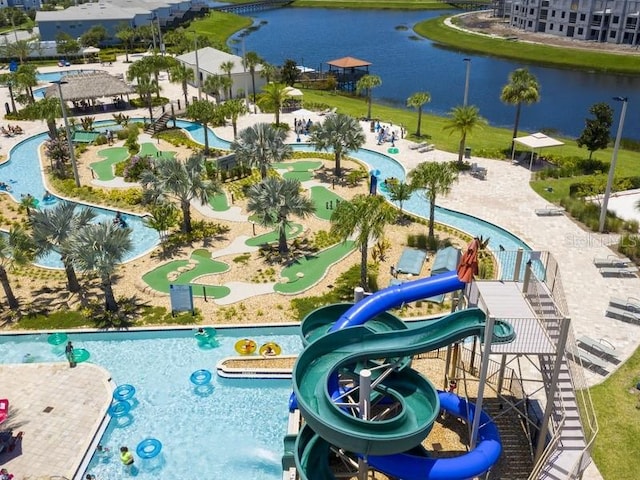 view of swimming pool with a water slide, a water view, and a playground