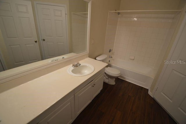 full bathroom featuring oversized vanity, tiled shower / bath combo, hardwood / wood-style flooring, and toilet