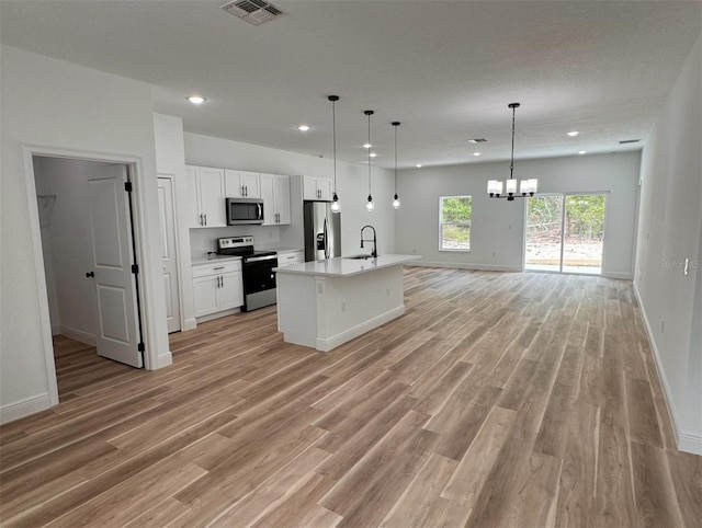 kitchen with light hardwood / wood-style flooring, decorative light fixtures, sink, white cabinets, and appliances with stainless steel finishes